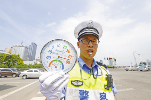 烈日下,江东交警大队民警老张戴着警帽,穿着警服,腰上挂着沉重的