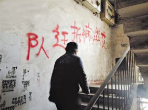 小区楼梯墙面上被喷涂"艾滋病拆迁队"的红字.